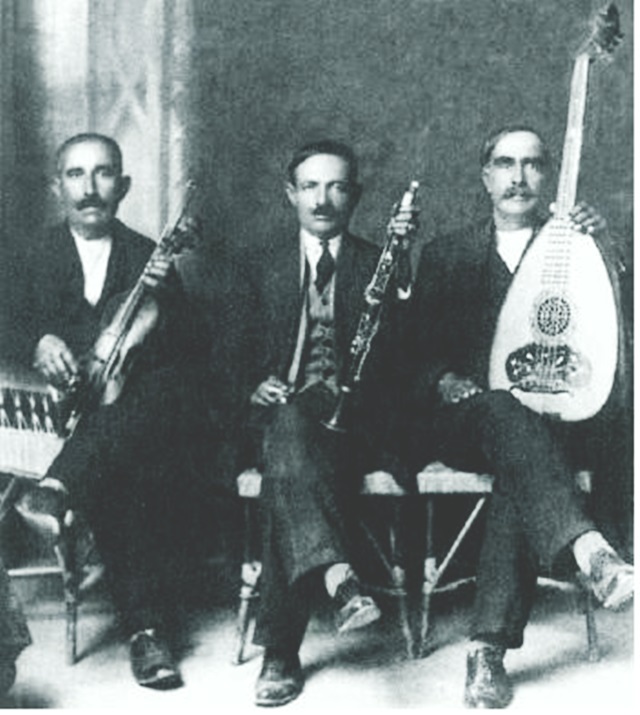 Ο σπουδαίος Πρεβεζάνος κλαριτζής Νίκος Τζάρας στην μέση, στα 1930, ο οποίος καλούνταν τακτικά σε Λευκαδίτικα πανηγύρια στην διάρκεια του μεσοπολέμου, ενώ δίδαξε σε αρκετούς Λευκαδίτες την τέχνη του κλαρίνου. Δεξιά του ο βιολιτζής Κώστας Μπενάτσης και αριστερά του ο λαουτιέρης Βασίλης Ντάλας. Η φωτογραφία είναι απ’ την ιστοσελίδα της Βουλής των Ελλήνων.