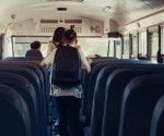 Energetic pupils leave academic shuttle. Friendly crowd go out school bus. Diverse multicultural students running out vehicle after studies. Professional driver sitting alone. Transport concept.