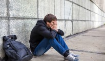 Sad Young Man sit by the Wall on the Street
