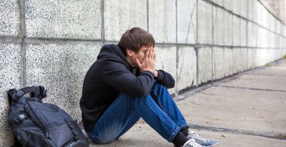 Sad Young Man sit by the Wall on the Street