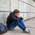 Sad Young Man sit by the Wall on the Street